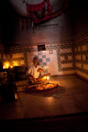 Priest sitting in front of a plate with offerings in Pindeshwor temple