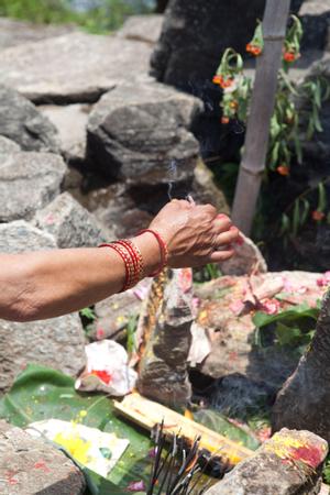 A woman lighting incense as offering at the place of worship for Khema at Tuwachung-Jayajum festival