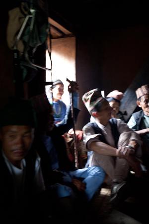 The ritual specialist, Prem Bahadur Rai (Salghare), and his crew are discussing while resting inside a house after the rituals are finished