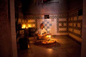Priest sitting in front of a plate with offerings in Pindeshwor temple