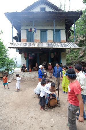 Boy beats the drum while villagers are dancing sakela in the courtyard